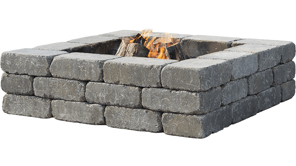 Angled product image of the Quarry Stone Fire Pit displayed against a transparent background. The square pit is built from three even layers of weather-resistant, tumbled concrete blocks in a cool mid-grey shade with speckled white veining. Each block has softly rounded corners and a subtly textured surface that mimics natural stone. At the centre, several split firewood logs burn with steady orange and gold flames, their light reflecting off the slightly matte block finish. The piece highlights rustic craftsmanship and durable design—perfect to complement your space with a rustic fire pit that invites warmth and togetherness.