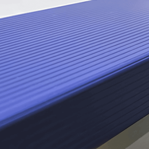 Close-up angled view of the Dark Blue coping option for the Endless Pools SP105 Modular Pool, featuring a clean, modern edge design with fine horizontal grooves running consistently across the surface. The rich navy blue tone enhances the sleek, contemporary aesthetic while providing a slip-resistant texture for improved safety and durability along the pool perimeter.