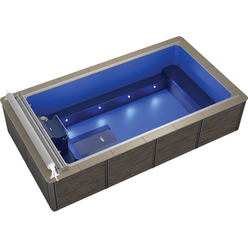 Overhead angled view of the Endless Pools EP508 Plus Modular Pool, displaying the vibrant blue interior with integrated underwater LED lighting along one long side, illuminating the swim area. The propulsion system and swim current grille are positioned at the shallow end, with a wide underwater bench seat spanning the opposite end. A stainless-steel roll-up cover assembly sits above the propulsion unit.