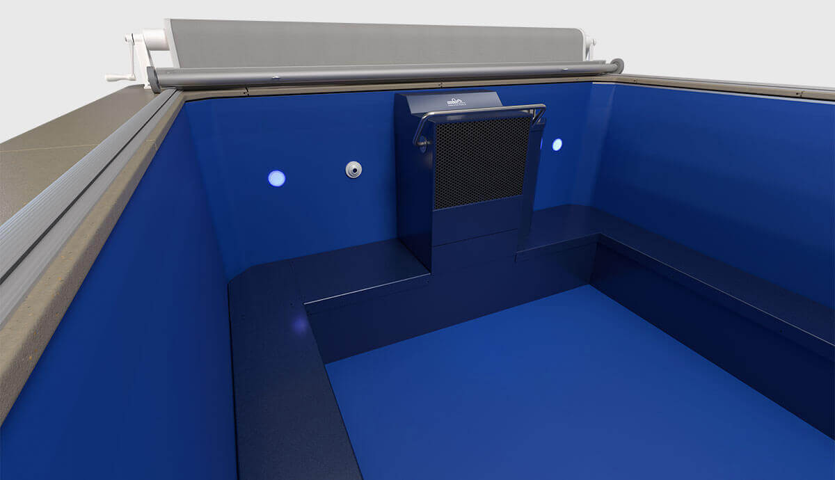 Close-up interior view of the Endless Pools EP508 modular pool, highlighting the vibrant blue interior liner and centrally mounted Hydrodrive™ propulsion system with protective black mesh grille. Two round underwater LED lights flank the system for illumination, with a discreet water return fitting on the left wall, and the silver pool cover roller positioned above the propulsion unit.