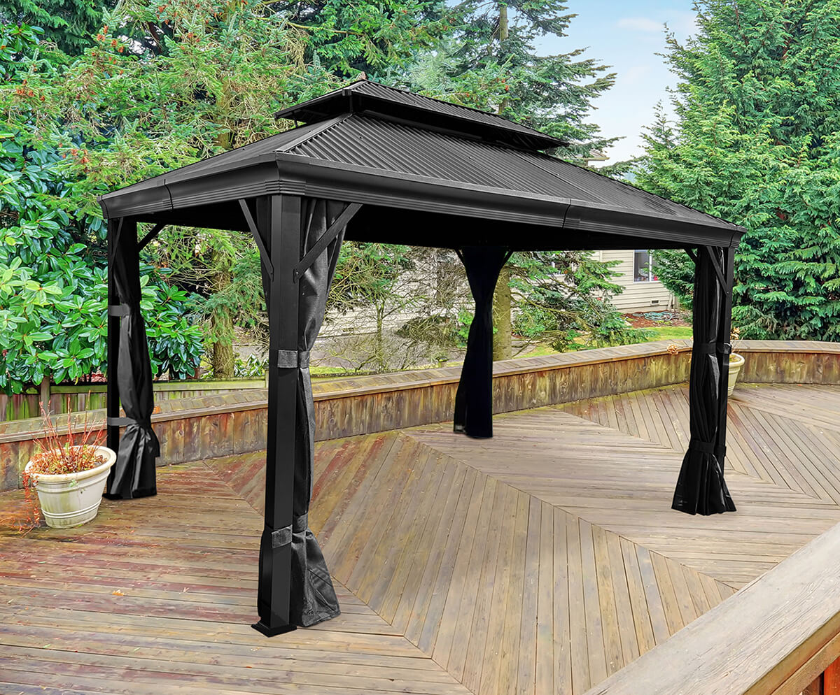 Standalone Maestrale Gazebo in a grey finish shown on a plain white background. The structure has a pitched double-tiered roof made from durable Galvalume® metal panels, with the upper vented roof providing added ventilation. Four square aluminium support posts with fashionable base covers hold the structure, with sheer black mesh mosquito curtains draped down from the canopy frame and tied back around each post. The clean, symmetrical design highlights the gazebo’s durability and minimalist aesthetic.