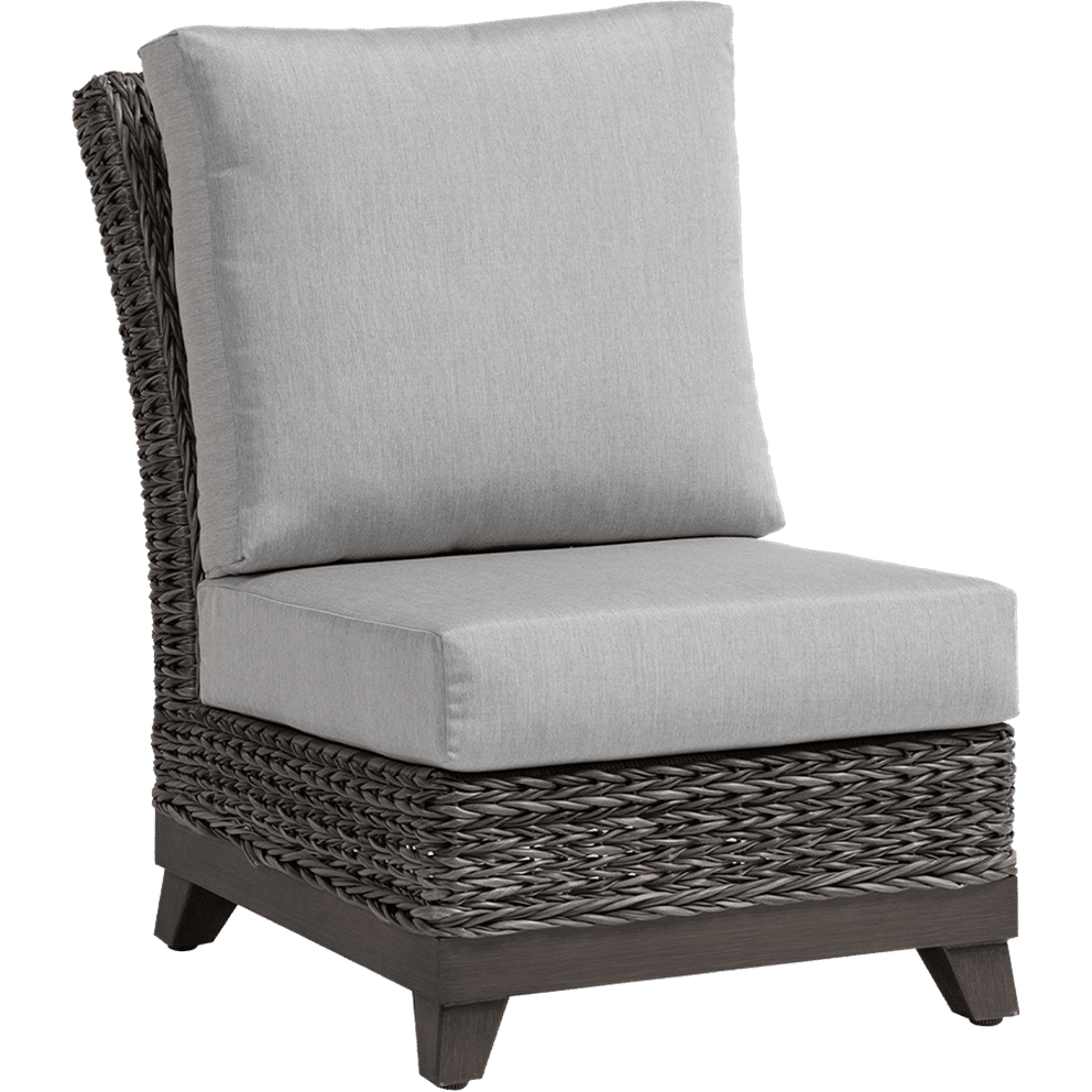 Angled perspective of the Asheville Furniture Collection armless section, emphasising the depth of the grey Sunbrella cushions with a tall, supportive back and thick, rectangular seat cushion. The woven resin wicker frame in weathered grey tones wraps around the seat base in a broad, hand-crafted pattern. Raised on dark wooden legs, the chair exudes durability and blends contemporary comfort with natural style.