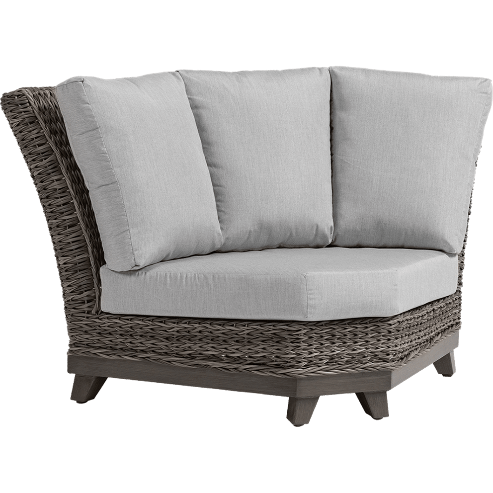 Angled front-left view of the Asheville Furniture Collection Curved Corner Section. The piece features a wide, deep seat with thick, light grey Sunbrella cushions for both the seat and backrest. Three tall, plush back cushions line the inner curve, providing full support across the back and sides. The frame is crafted from weather-resistant resin wicker in a warm grey tone, woven in a textured pattern that mimics natural rattan. The base and short, tapered legs are made from dark wood-effect material, creating a grounded, sturdy look. The design offers an inviting open corner seating arrangement suitable for modular outdoor setups.