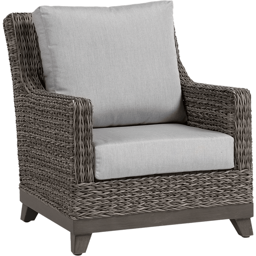 Angled perspective of the Asheville Lounge Chair from the Asheville Furniture Collection, showcasing its broad armrests and high supportive back with plush light grey cushions. The frame is wrapped in intricately woven wicker in warm grey tones, with the chair resting on a dark wooden base with short tapered legs, blending modern outdoor durability with classic comfort.