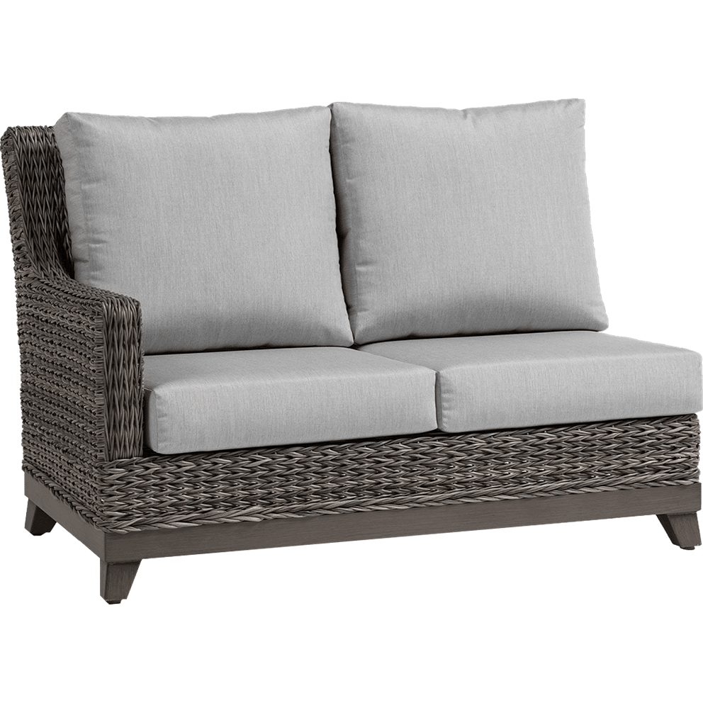 Outdoor Asheville Furniture Collection two-seat left sectional piece shown from an angled view. The frame is crafted from handwoven weathered grey resin wicker with a realistic rattan texture, supported on dark brown tapered resin base legs. Two wide Sunbrella seat cushions and two tall, plush Sunbrella backrest pillows in light grey provide deep seating comfort. The left side has a gently curved armrest, woven in the same wicker pattern, while the right side remains open to connect seamlessly with other modular pieces.