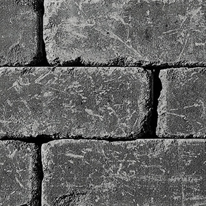 Close-up of the Charcoal colour option for the Quarry Stone Fire Pit, showing stacked rectangular concrete blocks in deep charcoal grey. The surface has a rugged, weathered texture with subtle lighter scuff marks and natural imperfections that highlight the handcrafted stone effect. Each block’s edges are slightly softened, giving the fire pit a timeworn, authentic appearance.