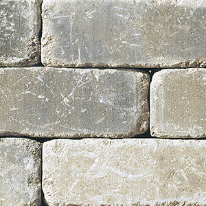 Close-up of the Sierra Grey colour option for the Quarry Stone Fire Pit, featuring light grey concrete blocks with warm beige undertones. The stones have a naturally aged texture with visible surface markings and slight tonal variation, creating a sun-bleached, rustic look. The uneven, lightly distressed finish adds depth and realism to the stacked stone aesthetic.