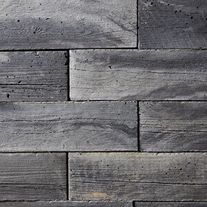 Close-up of the Weathered Grey colour option for the Bridgewood Fire Pit, featuring horizontally stacked concrete blocks with realistic woodgrain textures. The cool grey tones are accented by darker streaks and surface variations, replicating the appearance of naturally weathered wood. The texture includes delicate grooves and organic imperfections that add depth and authenticity to the fire pit’s timber-inspired design.