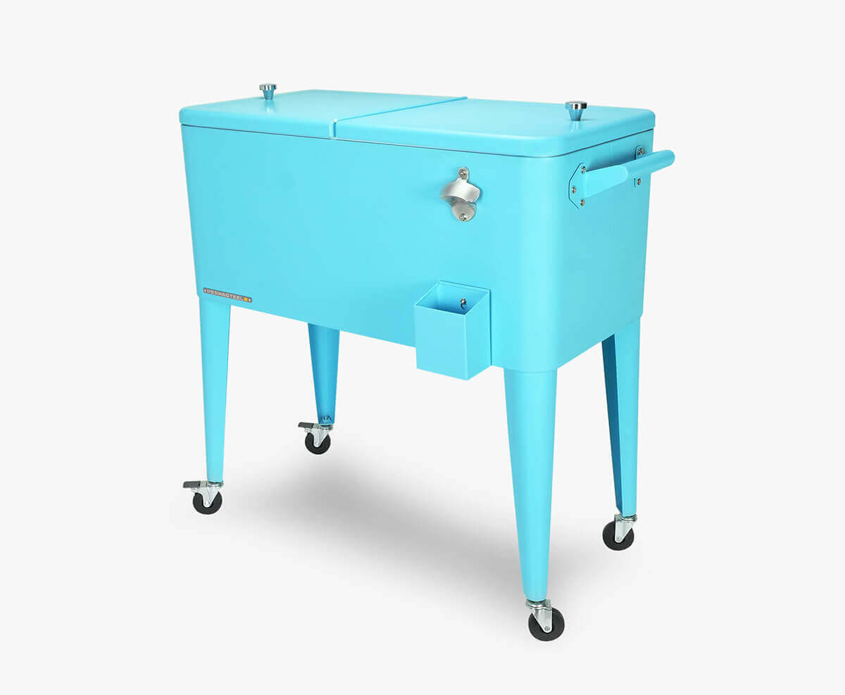 Angled view of the Permasteel 80-quart cooler with wheels in bright turquoise blue, featuring a rectangular steel body with a split-lid design. The cooler stands on four tapered metal legs with chrome casters for mobility. A silver bottle opener and small cap catcher tray are mounted on the right side, while matching handles extend from each end. The clean, modern silhouette combines vintage charm with durable construction, ideal for outdoor entertaining.