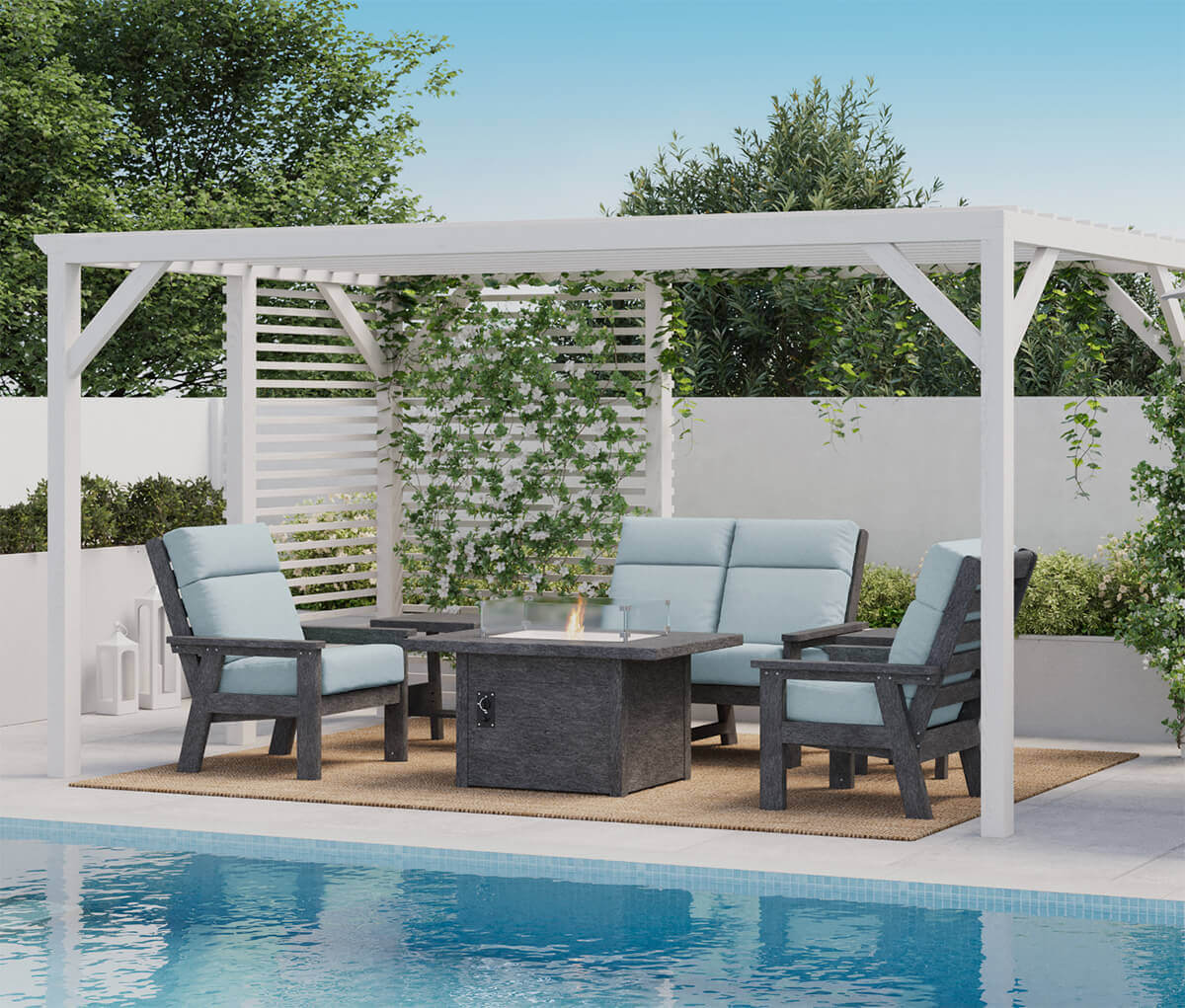 A modern poolside scene showcasing the CRP rectangular fire table with its flames lit behind the clear wind guard. Four pale blue cushioned chairs surround the fire table under a white pergola. The sleek recycled plastic construction stands out against the pool’s blue water and surrounding greenery. Soft reflections from the flames shimmer across the tabletop and glass.