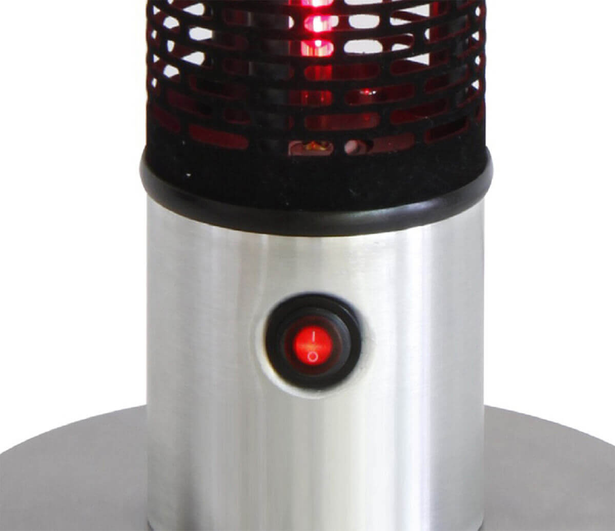 A close view of the lower section of the HEA21212 Portable Heater focusing on the stainless steel cylindrical base and the illuminated red power switch. The black perforated grille above the base reveals the glowing red infrared heating element. The brushed metal surface of the base is smooth and reflective, curving gently into the round platform that stabilises the heater. The red power switch sits inset into the metal, clearly showing the on position.