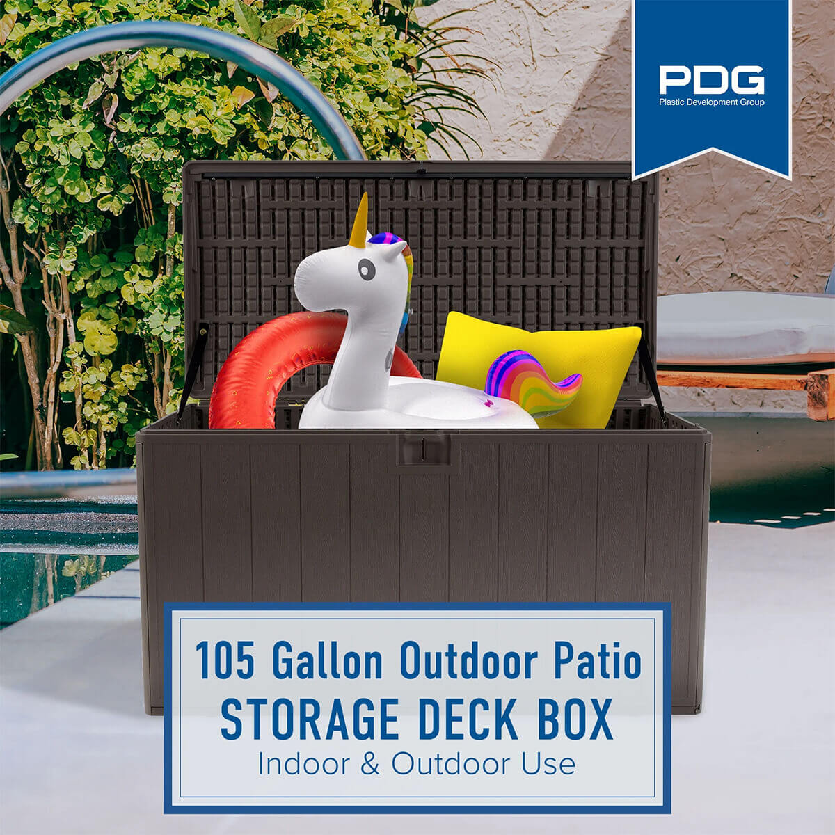 PDG 105 Gallon Resin Outdoor Storage Deck Box displayed poolside with the lid fully open, revealing interior storage filled with bright pool floats including a large white inflatable unicorn with a rainbow tail, a red circular float, and a yellow cushion. The inner surface of the lid shows a textured grid-style reinforcement pattern. A PDG banner sits in the upper right corner, while a framed text box at the bottom reads ‘105 Gallon Outdoor Patio Storage Deck Box, Indoor and Outdoor Use.’ Lush poolside plants and a curved metal pool ladder are visible in the background.