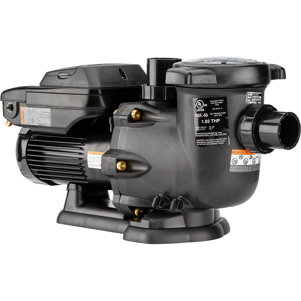 Angled rear three quarter view of the Hayward TriStar VS Variable-Speed Pool Pump, isolated on a transparent background, with the wet end on the right and the motor on the left. The strainer pot sits high on the right with a round lid and side tabs, and a large threaded union port projects straight out toward the right edge. A tall vertical discharge outlet rises near the top centre, behind the volute. The side of the wet end shows multiple brass toned inserts and hex head fasteners around the clamp ring. The motor extends leftward with pronounced cooling fins and a long rectangular control box on top, its lid closed, with warning labels and a white information sticker along the side. At the far left, the rounded motor end bell and fan cover are partly visible. The pump rests on a wide, rounded base rail with a slightly arched profile and broad feet.