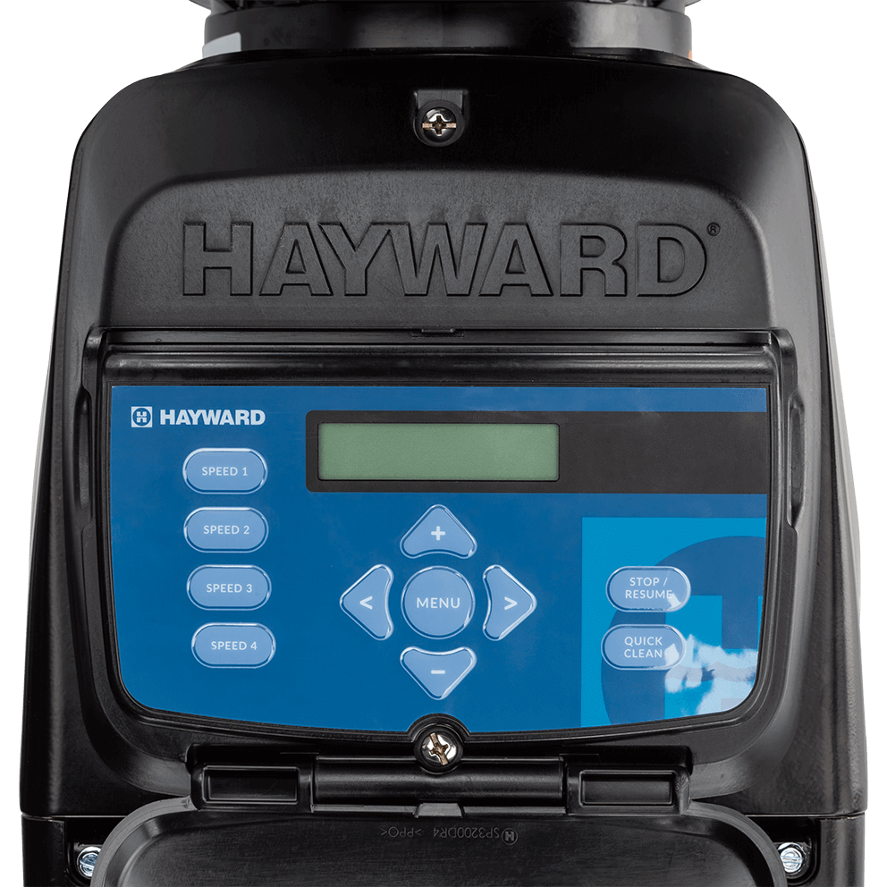 Close up front view of the Hayward TriStar VS Variable-Speed Pool Pump control interface, isolated on a transparent background, with the cover open. The black outer housing frames a blue keypad panel featuring a rectangular LCD display window near the top centre, a circular menu button and directional arrows in the middle, four labelled speed buttons stacked vertically on the left, and two larger function buttons on the right. A small Hayward logo appears in the top left of the blue panel, while the lower edge shows the hinged door lip and a central fastener beneath the keypad.