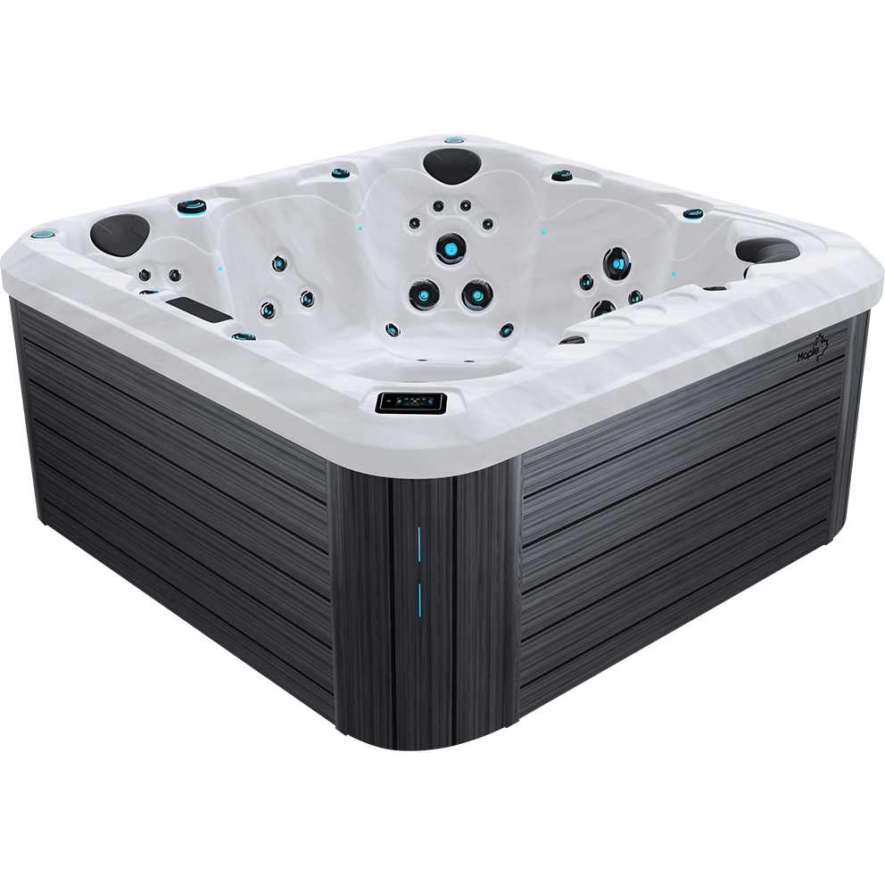 Angled front right three quarter view of the Maple Spas M950 Premium 7-Person Hot Tub showing the full acrylic shell and cabinet structure with no visible background. The white marble effect acrylic interior features seven contoured seating positions arranged around a central footwell. At the back centre is a deep captain style seat with a large circular cluster of hydrotherapy jets positioned at mid back height, surrounded by smaller accent jets placed symmetrically above and below. To the left and right of this seat are upright therapy seats with grouped mid back and lower lumbar jets. The front right corner contains a sculpted lounge style seat with multiple jets aligned along the backrest and calf area, while the opposite side includes additional upright seating with clustered shoulder and back jets. A raised square foot dome sits in the centre of the floor, fitted with evenly spaced foot massage jets arranged in a circular pattern. Black cushioned headrests are positioned along the upper rim at select seating locations. Blue LED illuminated jet rings and perimeter accent lighting are visible throughout the shell. The digital control panel is embedded into the top front edge of the acrylic lip, slightly left of centre, with a rectangular black interface. The exterior cabinet panels are finished in a horizontal grey wood grain pattern, and a vertical illuminated accent strip appears on the front corner panel. The Maple leaf logo badge is mounted on the upper right cabinet panel.