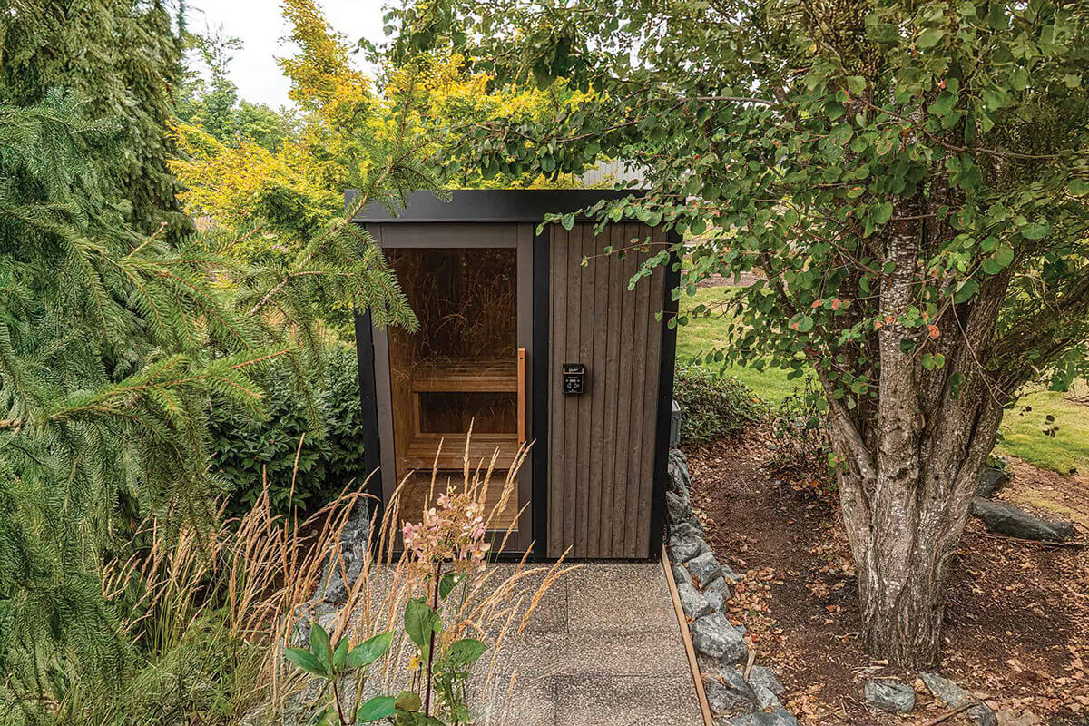Outdoor Visscher Luxe Sauna in a Winnipeg garden: Front-facing view with snow-load roof cap and digital control panel integrated into landscaping.