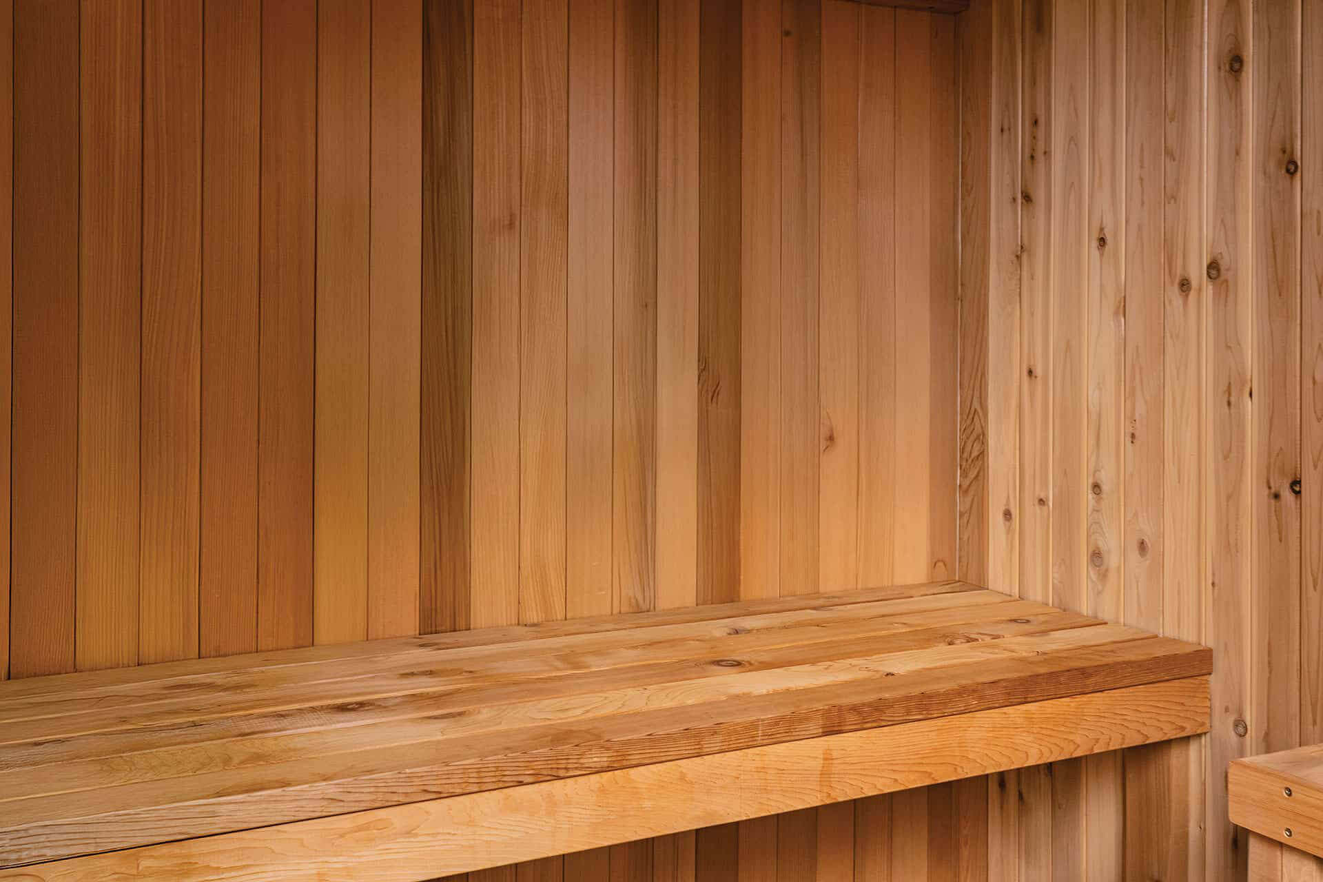 Visscher Luxe Sauna interior: Close-up of the premium Western Red Cedar bench planks and wall, showcasing the natural grain and honey-toned finish.